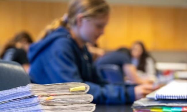 A child with notebooks stacked in front of her at school